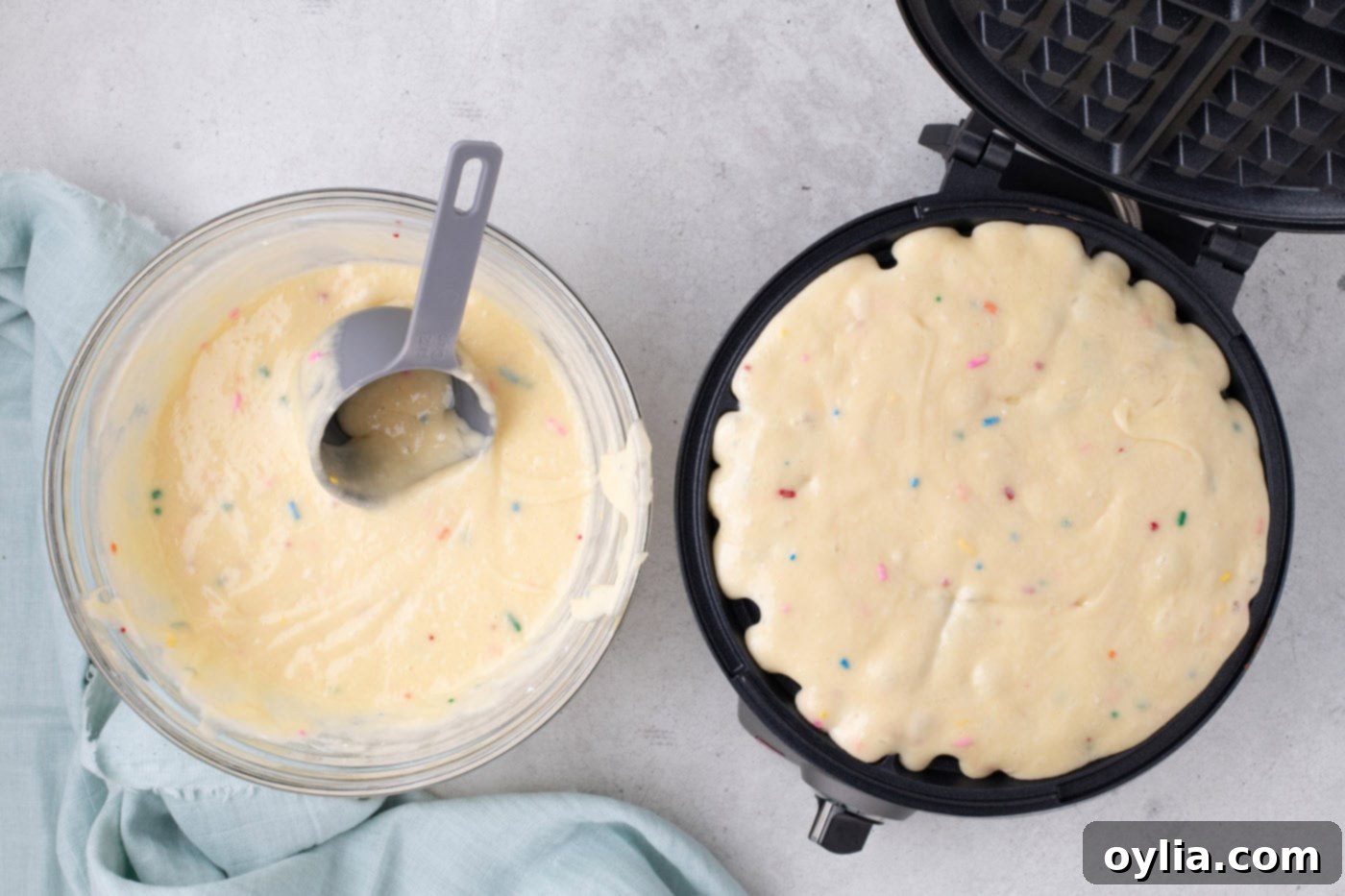 cake mix batter being poured into a hot waffle iron
