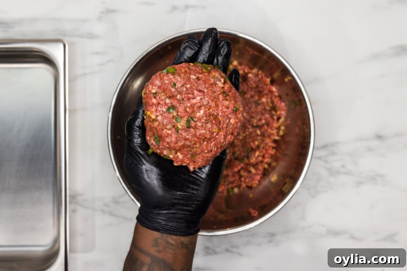 gloved hand holding burger patty