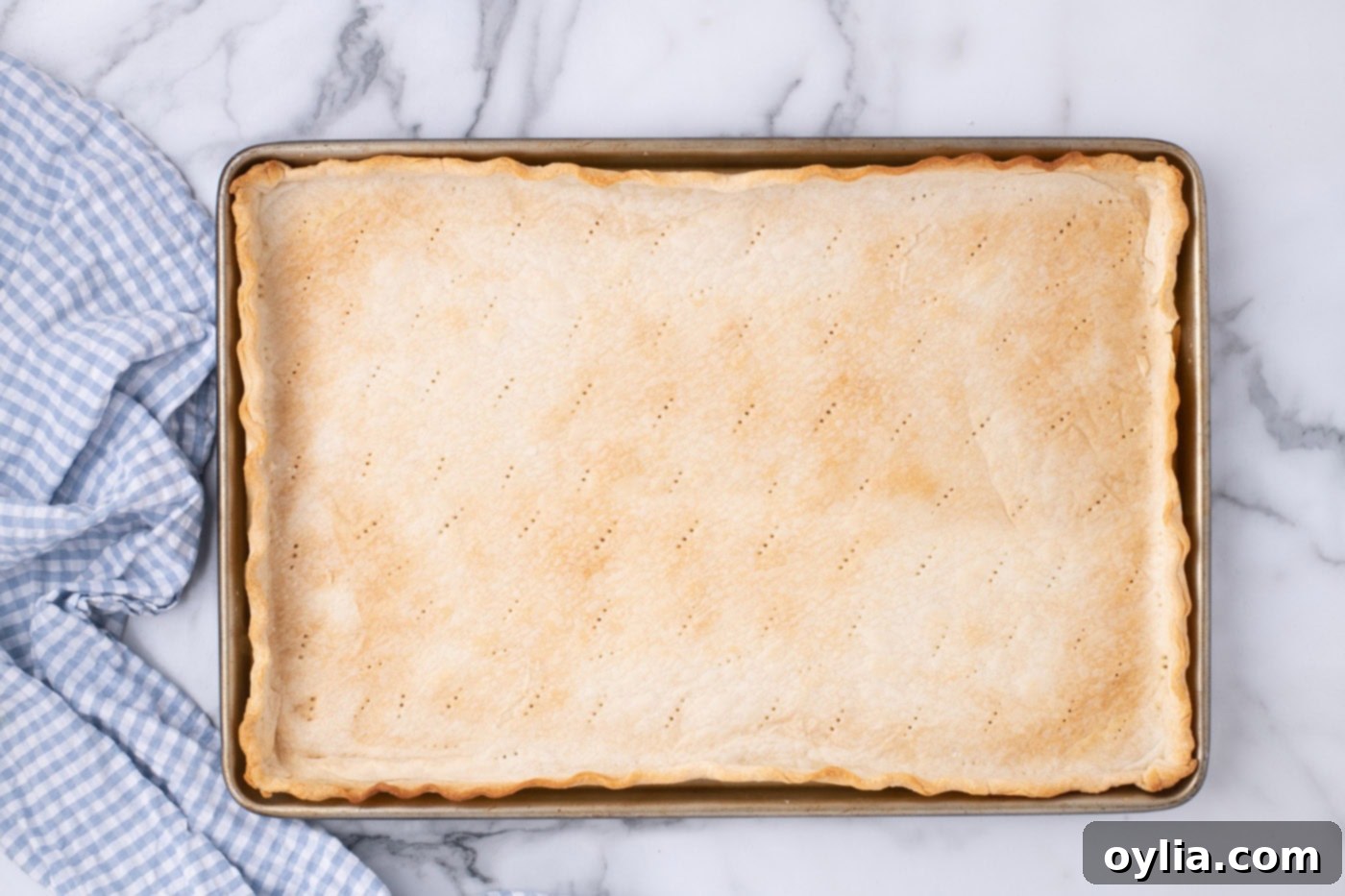 The golden-brown, fully baked pie crust cooling on a wire rack within its jelly roll pan.