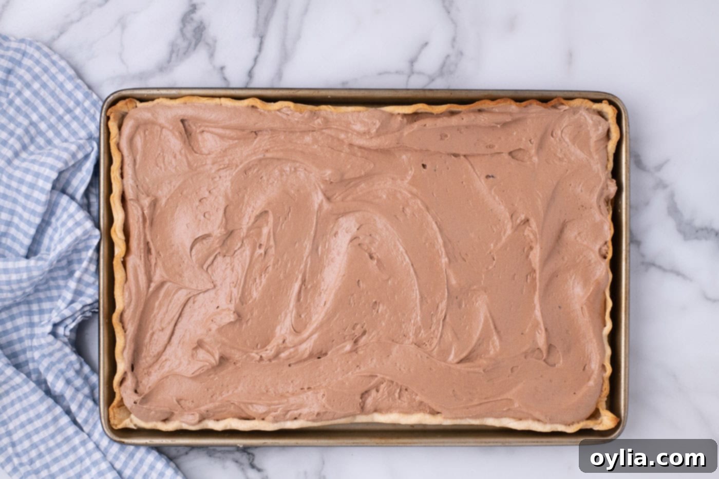 The smooth and creamy French silk pie filling evenly spread into the cooled, golden-brown pie crust in a jelly roll pan.