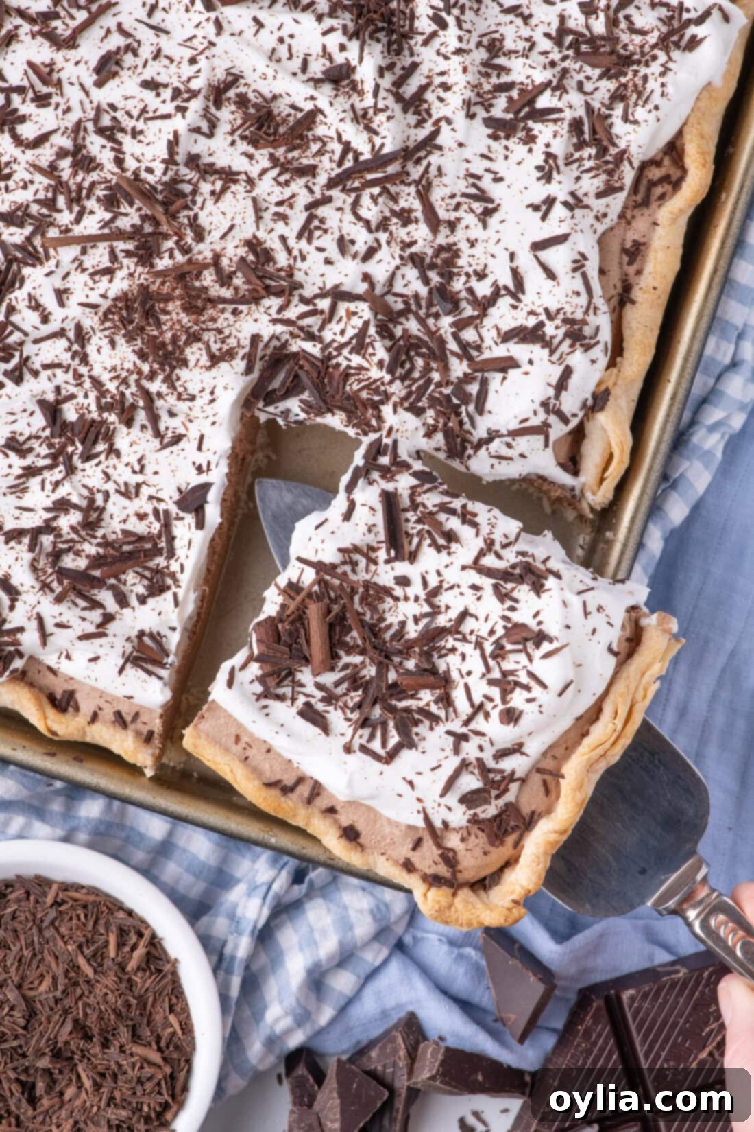A server carefully removing a perfectly cut slice from a large French Silk Slab Pie, highlighting its clean layers and generous size.