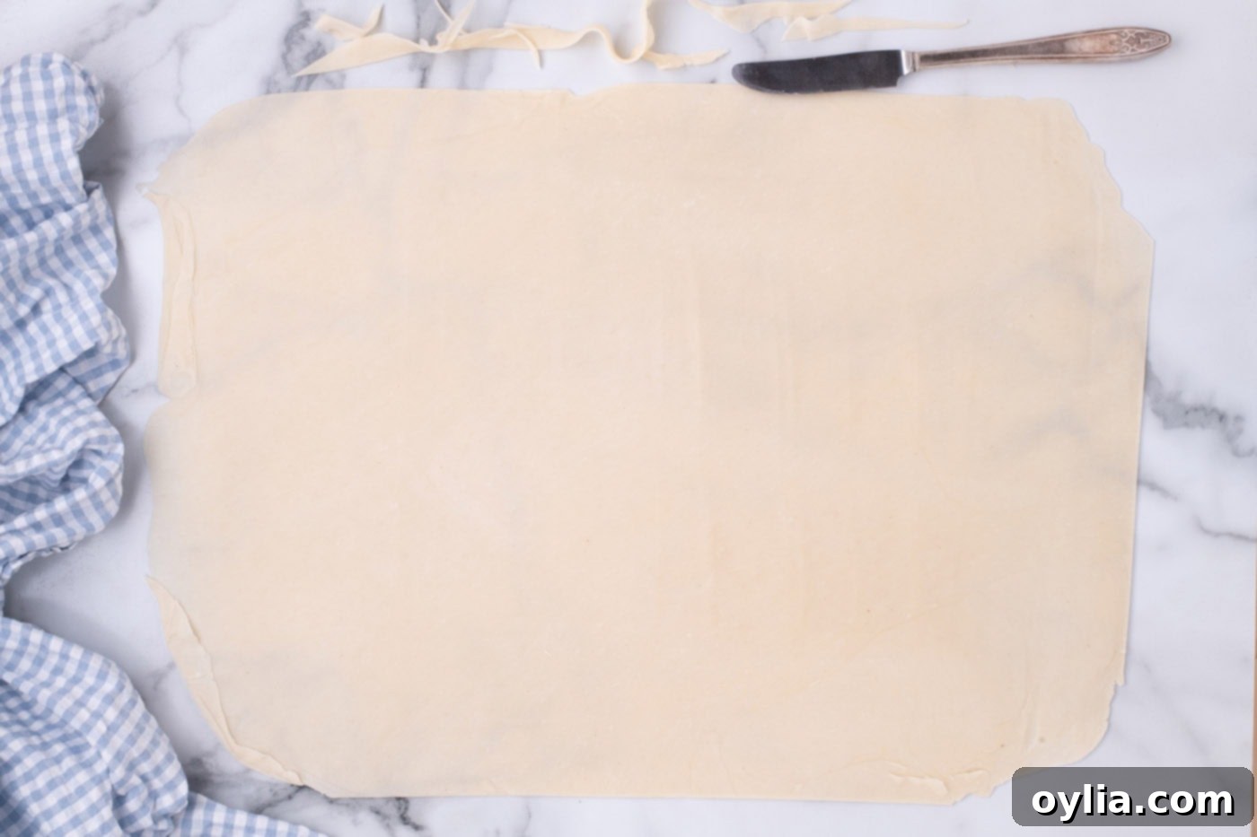 Pie crust dough rolled into a large rectangle, ready to be transferred to a sheet pan.