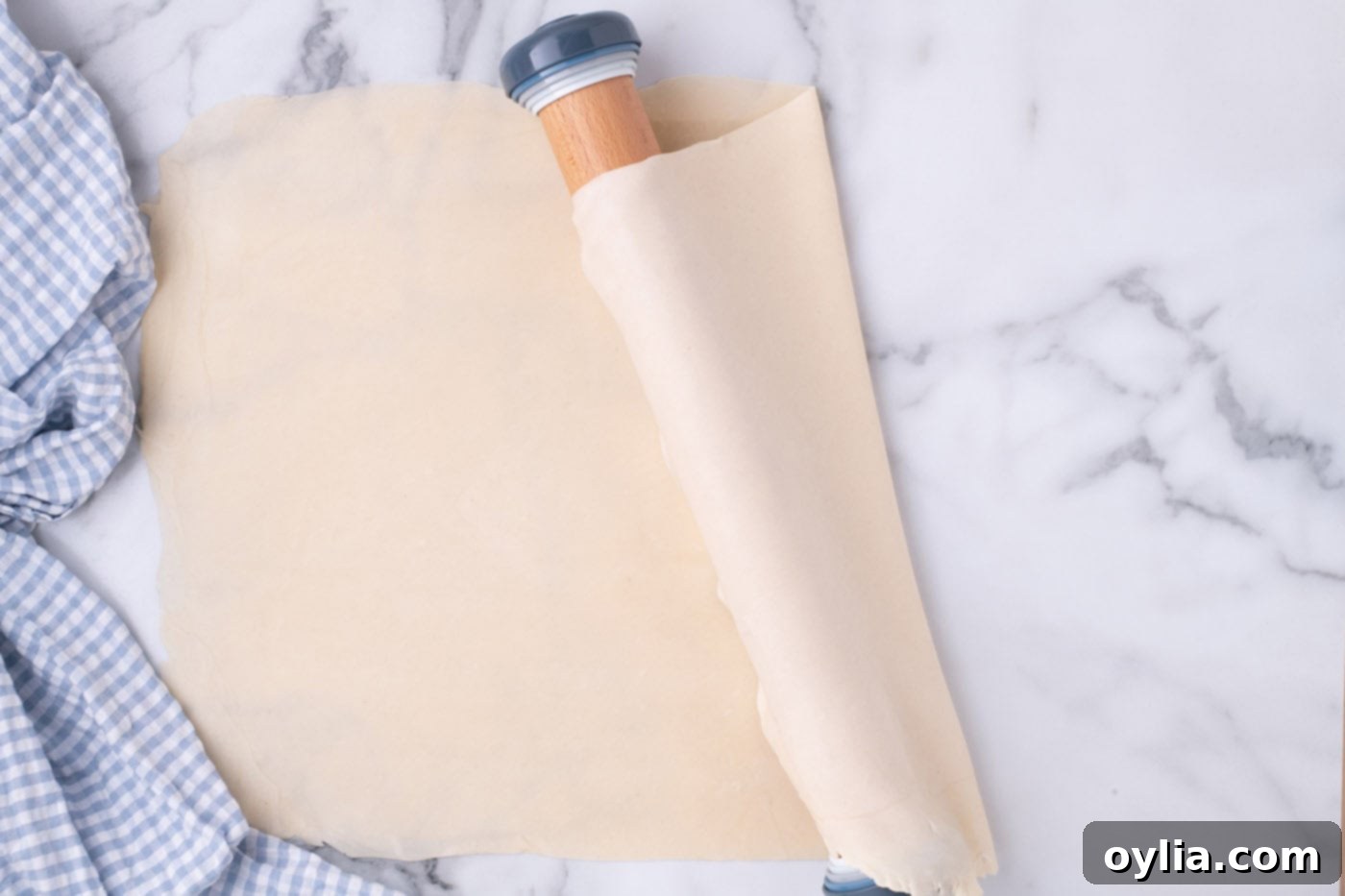 Pie crust being gently draped over a rolling pin, demonstrating the technique for easy transfer to the baking pan.