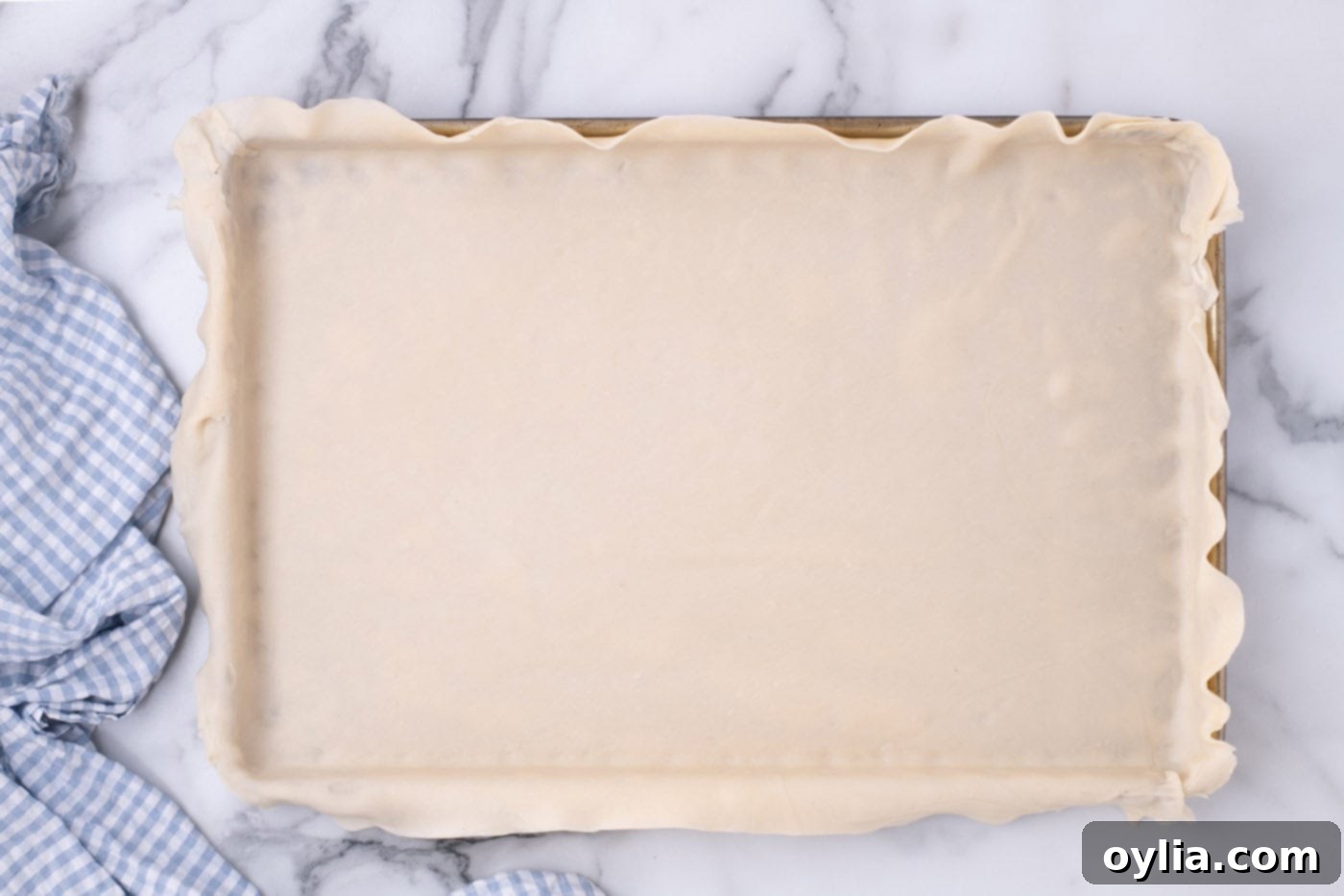 The pie crust successfully placed and fitted into a jelly roll pan, with edges ready for shaping.