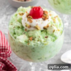 Close up photo of Watergate Salad in a bowl topped with cool whip and a cherry