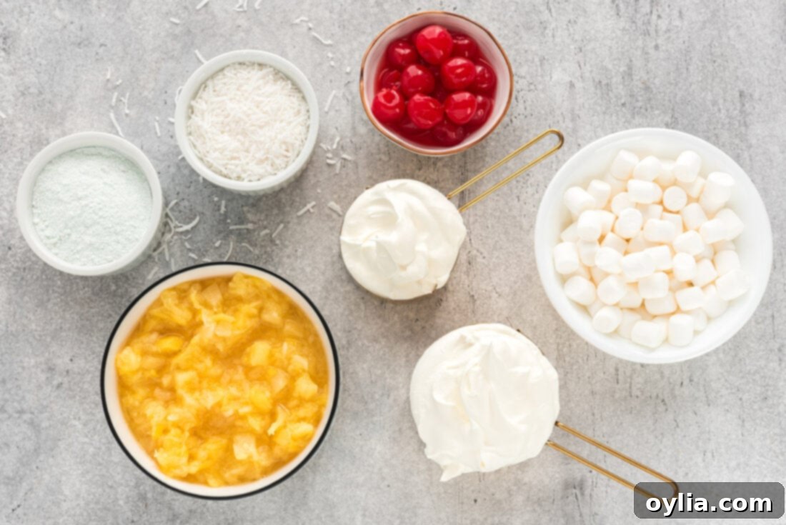 A flat lay of all the simple ingredients required to make Watergate Salad: a box of pistachio pudding, a can of crushed pineapple, a tub of Cool Whip, a bag of mini marshmallows, flaked coconut, and maraschino cherries.