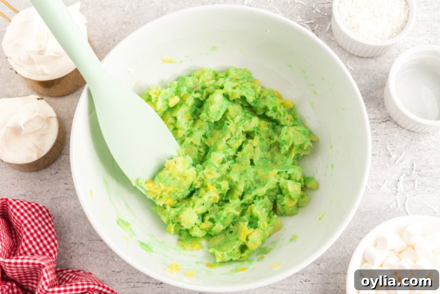 Pistachio pudding mix combined with crushed pineapple in a large bowl, forming a thick green mixture.