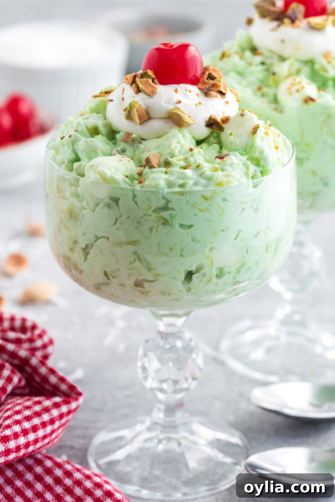 Close-up photo of Watergate Salad served in a clear sundae bowl, garnished with a single maraschino cherry, highlighting its creamy texture.