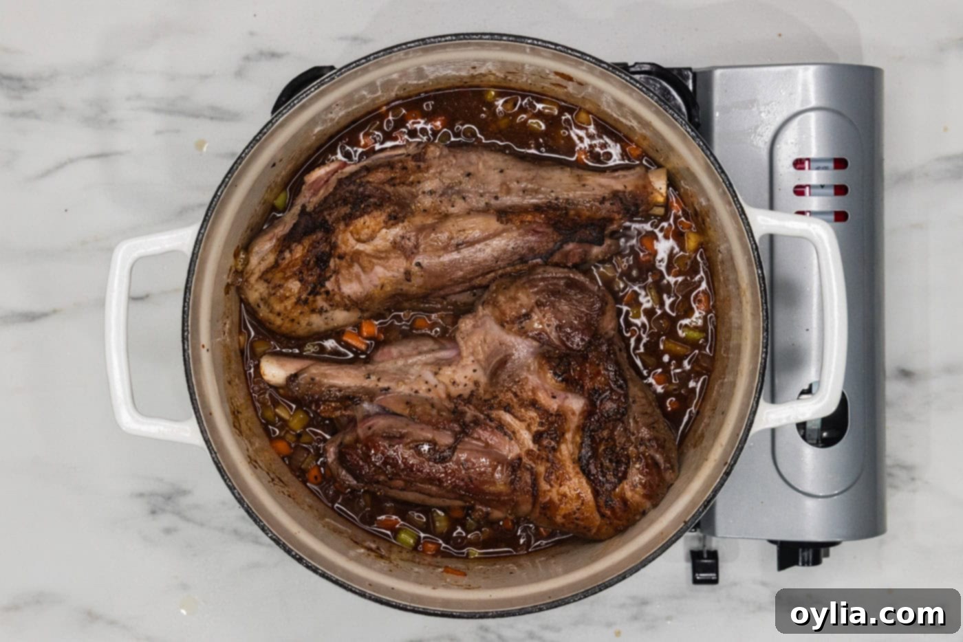 lamb shanks braising in red wine in a dutch oven