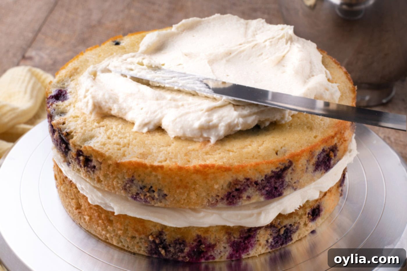 spreading cream cheese frosting over lemon blueberry cake
