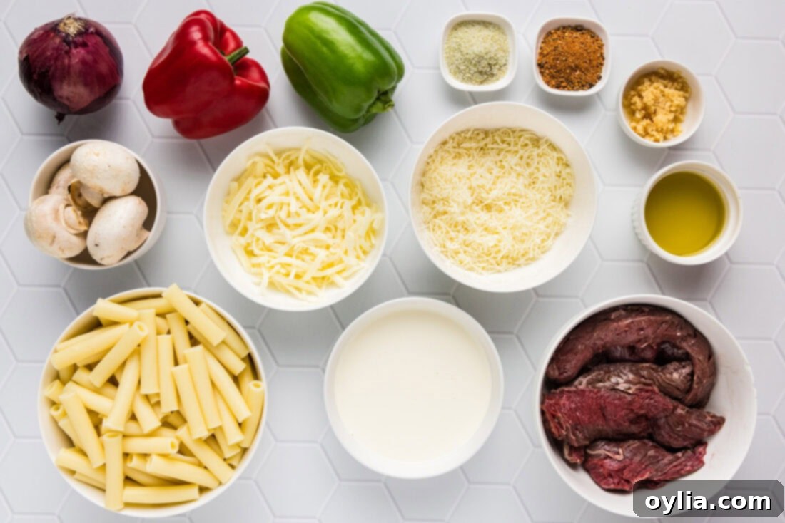 All ingredients for Philly Cheesesteak Pasta laid out, including steak, bell peppers, onions, mushrooms, pasta, and cheeses.