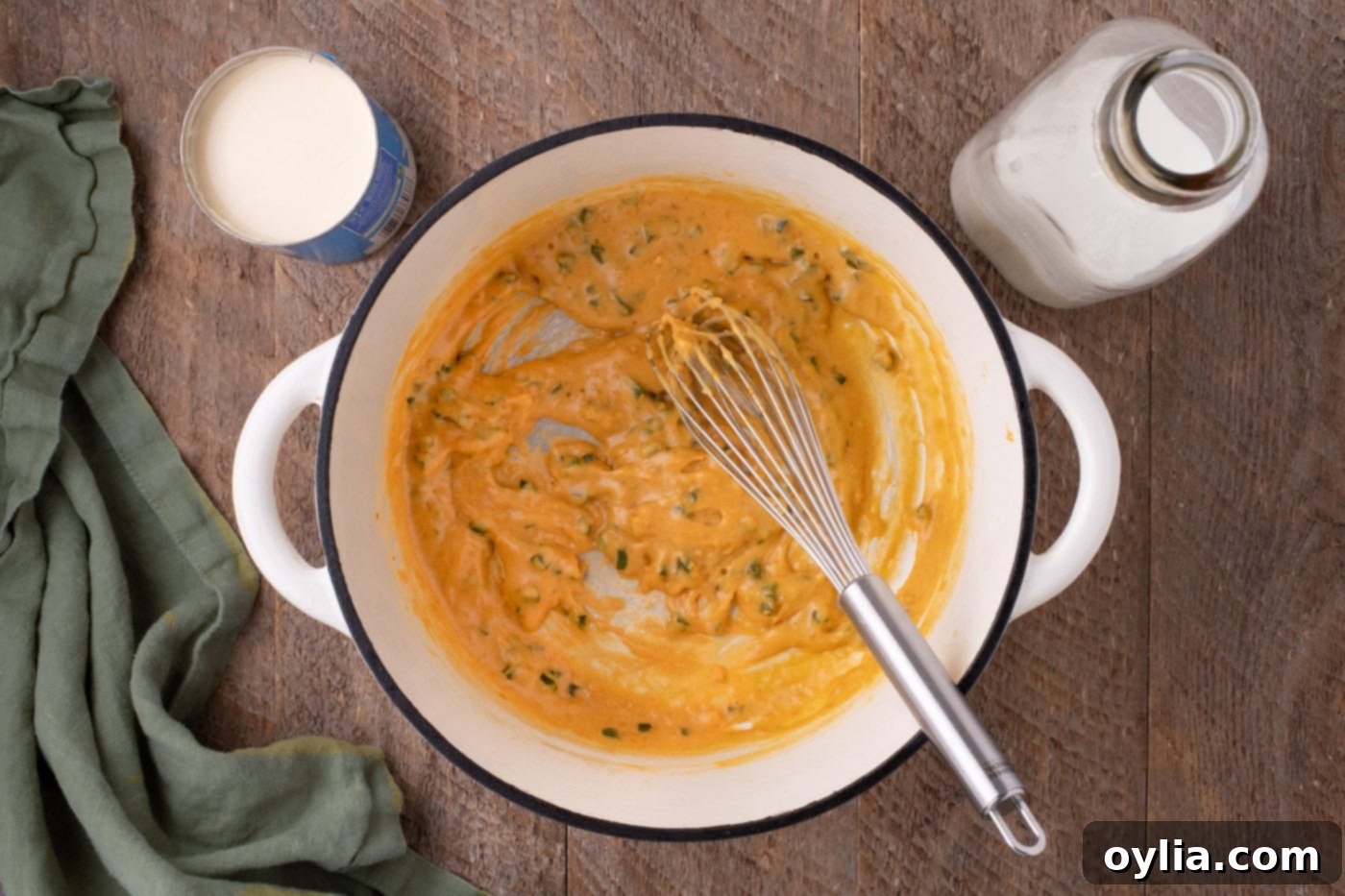 whisking evaporated milk into jalapeno mixture in a pot