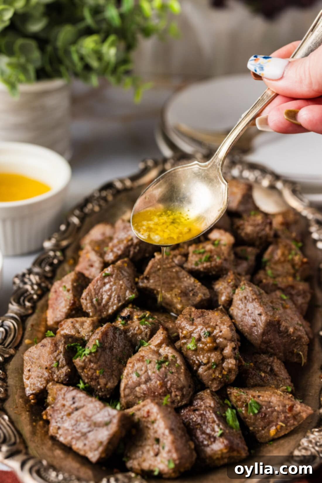 Your New Favorite Air Fryer Steak Bites 3 Delicious garlic butter sauce being drizzled over perfectly cooked Air Fryer Steak Bites on a platter.