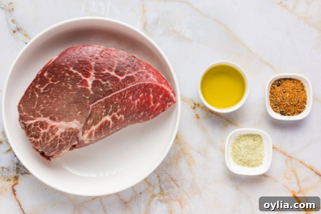 Your New Favorite Air Fryer Steak Bites 4 Essential ingredients for Air Fryer Steak Bites including raw sirloin, olive oil, and seasonings laid out on a wooden board.