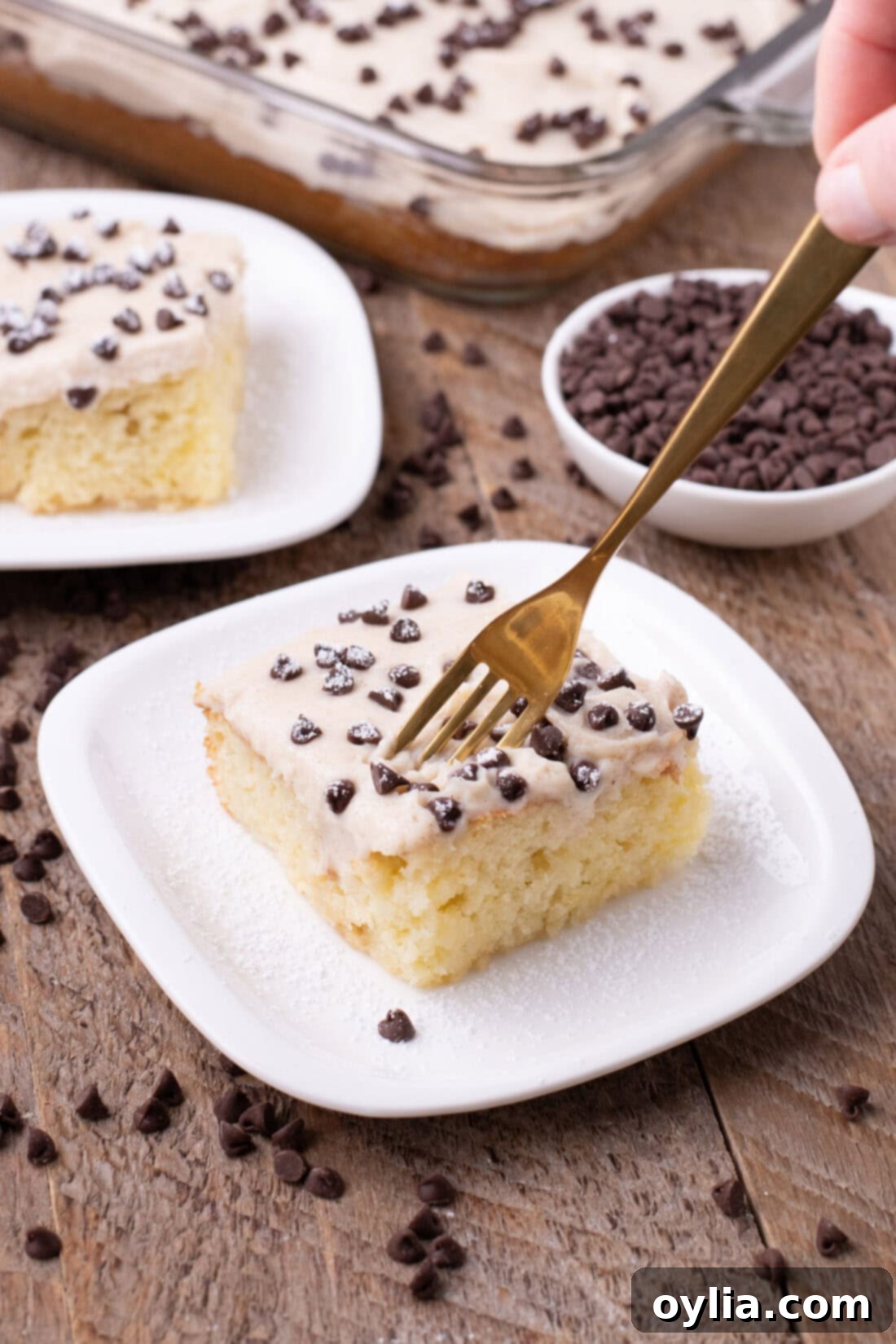 Fork cutting into a slice of Cannoli Poke Cake revealing moist cake and creamy topping