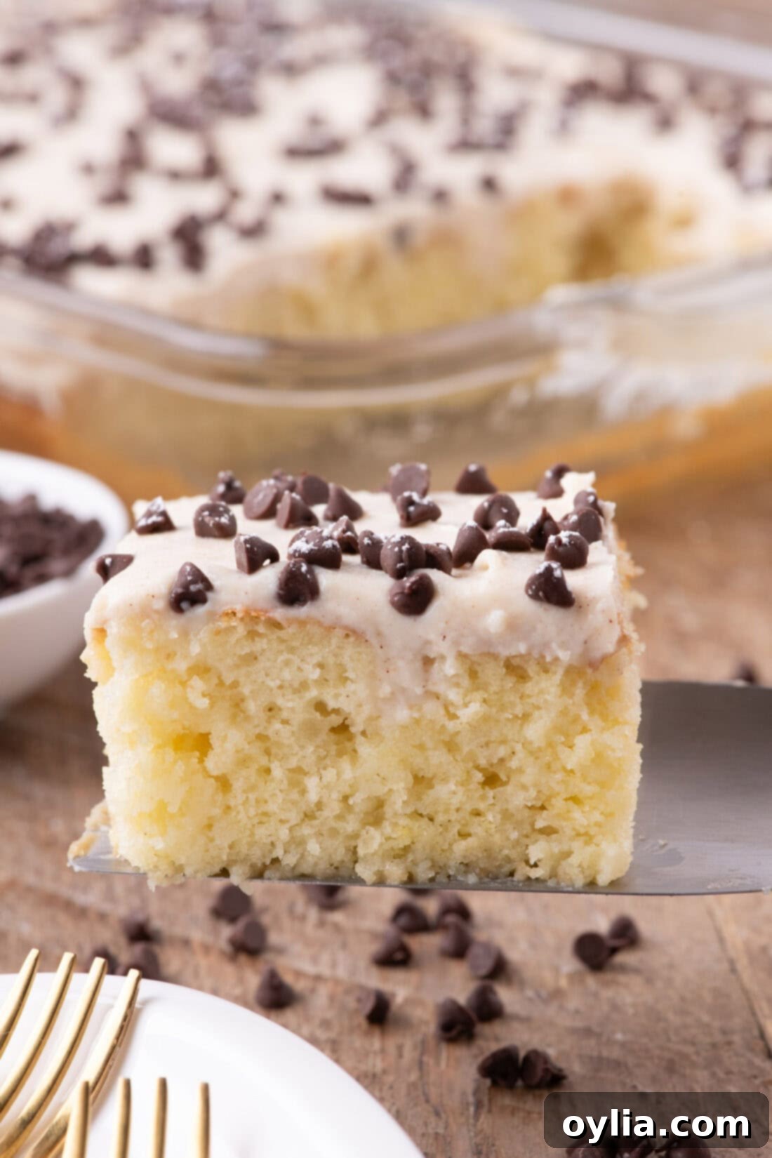 A perfectly sliced piece of Cannoli Poke Cake on a spatula, ready to be served