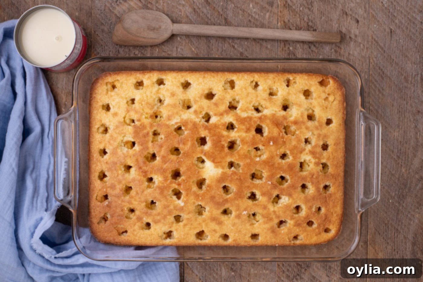 close-up of a warm baked cake with many holes poked into its surface