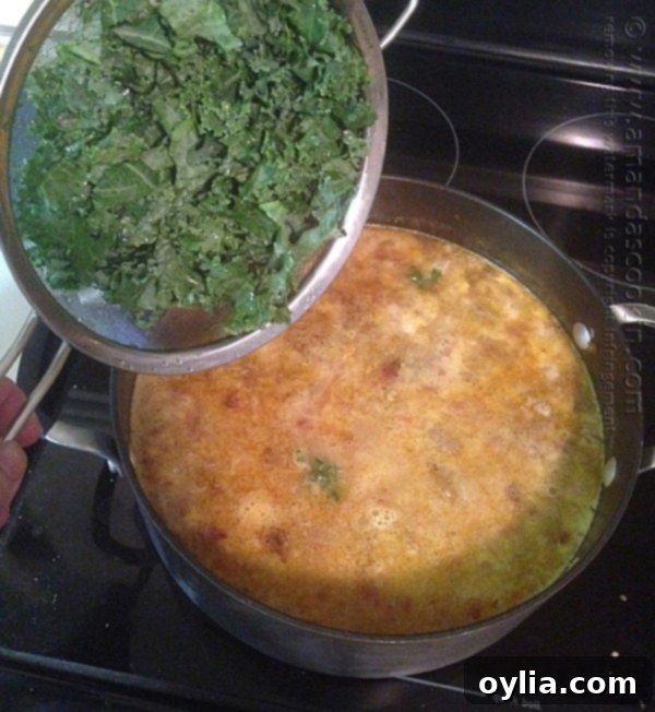 Adding fresh chopped kale to the simmering Zuppa Toscana soup