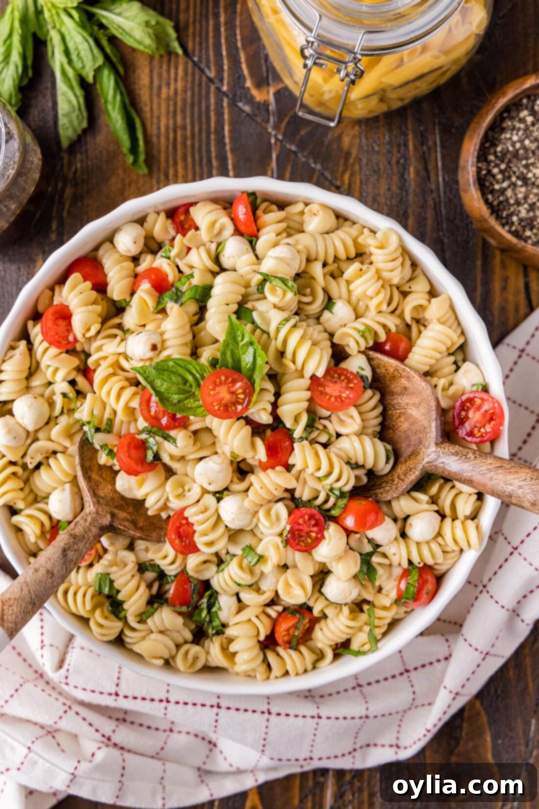 A large ceramic bowl filled with freshly mixed Caprese Pasta Salad, ready to be chilled or served, highlighting its vibrant colors and inviting texture.