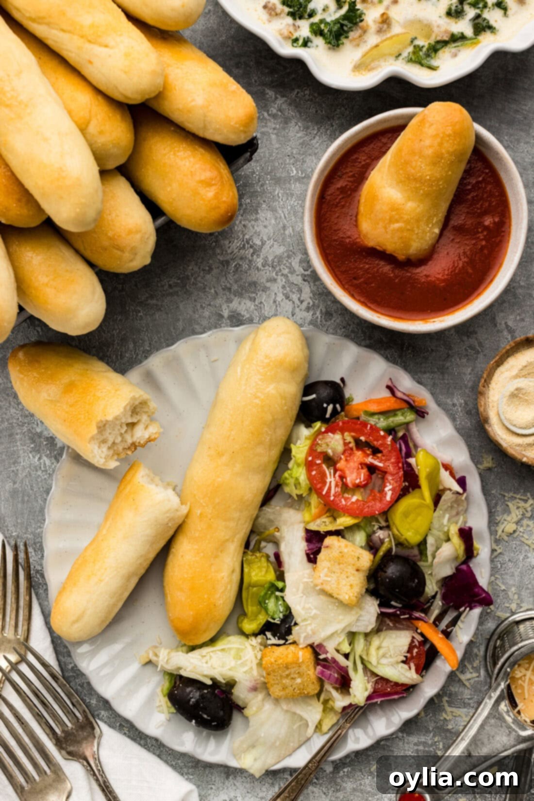 Olive Garden Breadstick broken in half on a plate with salad