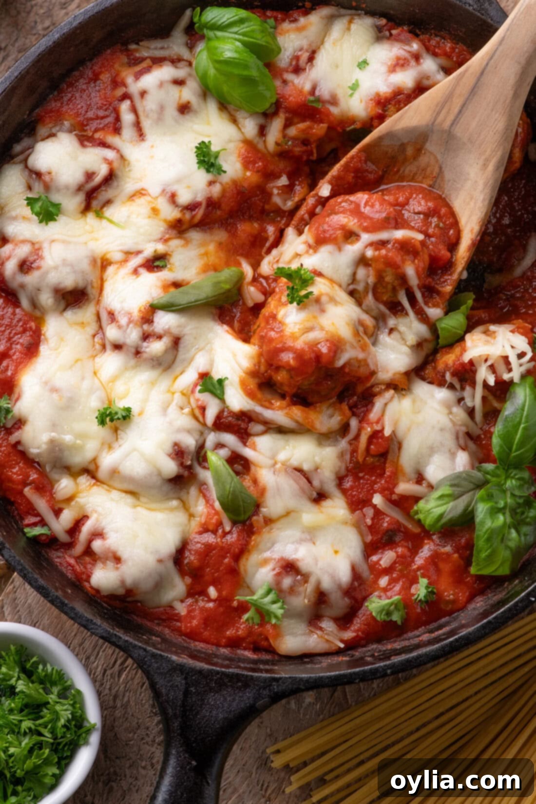 Close up photo of a spoon in a skillet of Chicken Parmesan Meatballs