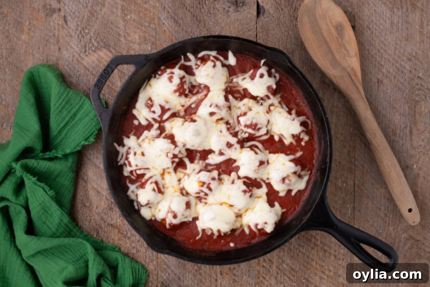 melted cheese over chicken parmesan meatballs in a skillet