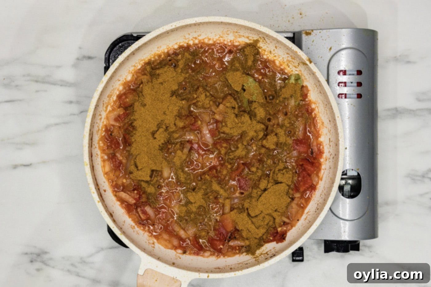 curry powder added to skillet with tomato based sauce