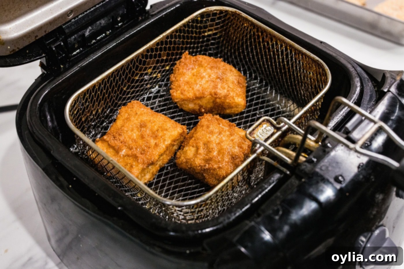 cooked cod patties in a deep fryer basket