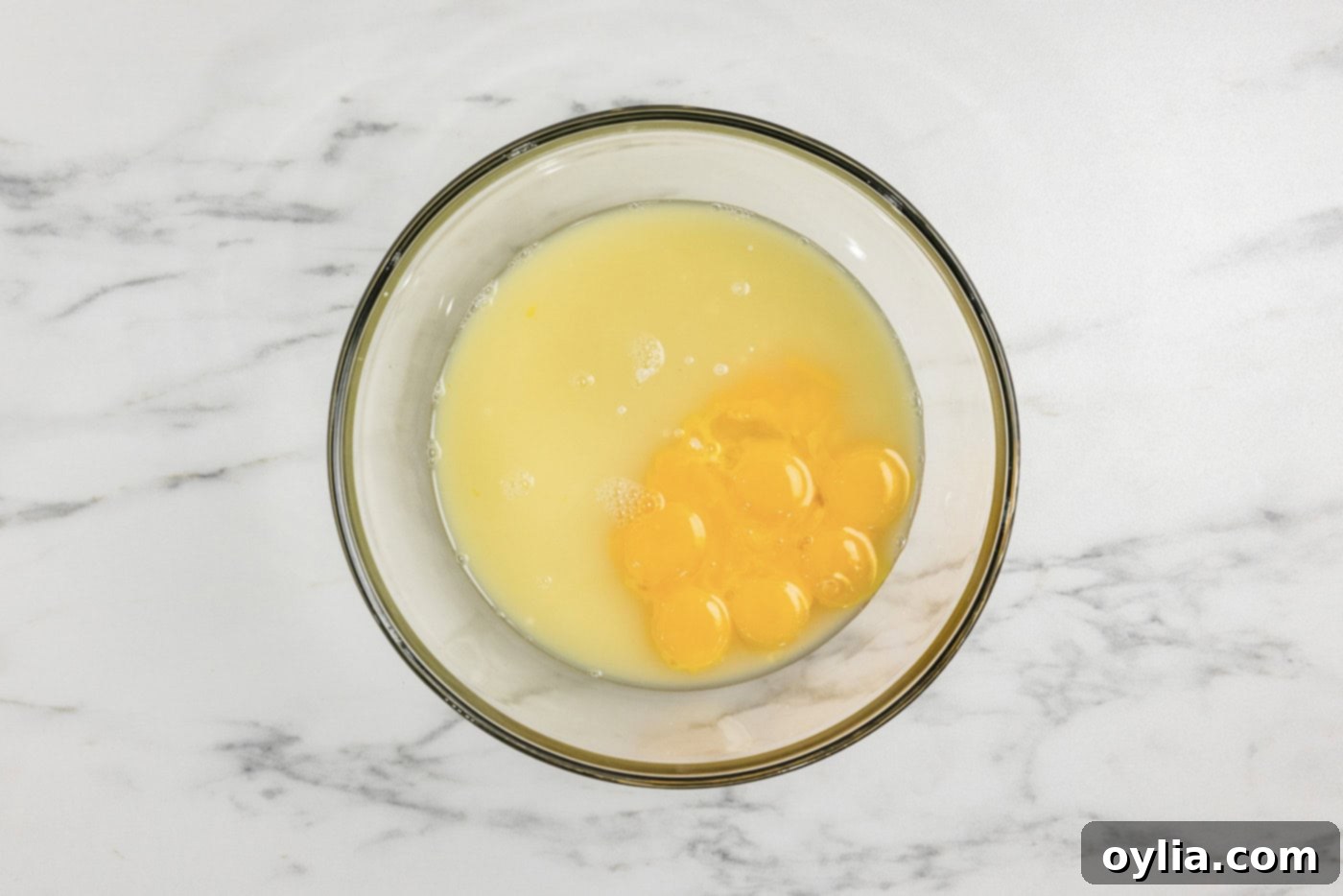 A bowl containing egg yolks, lime juice, and sweetened condensed milk, before mixing