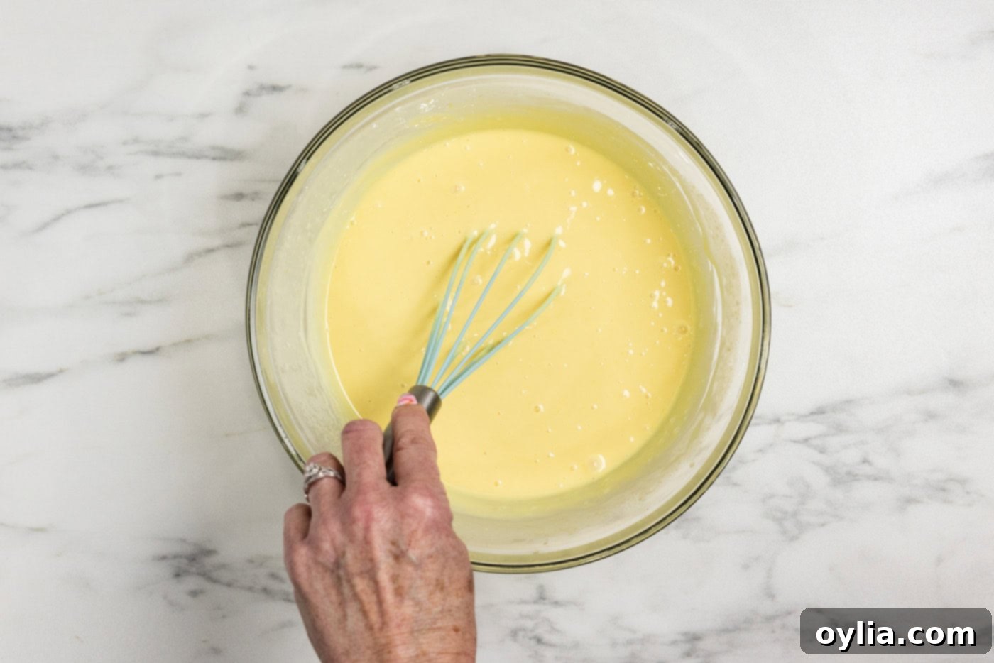 The key lime pie filling being whisked in a bowl until thick and creamy