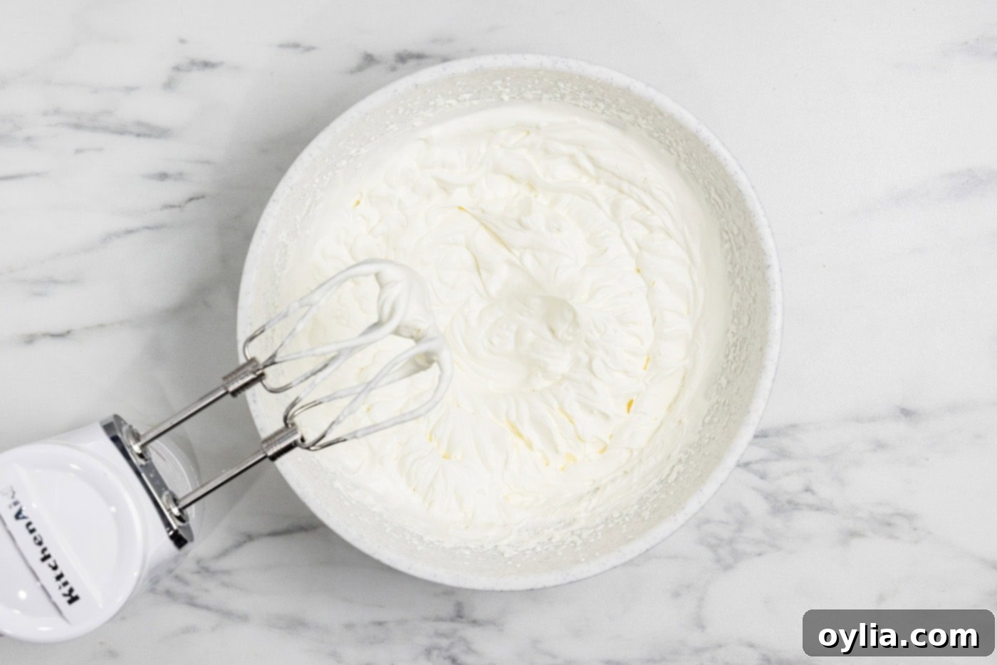 Freshly whipped cream in a bowl, being prepared with an electric mixer