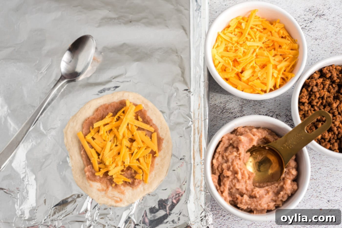shredded cheese over refried beans and biscuit dough