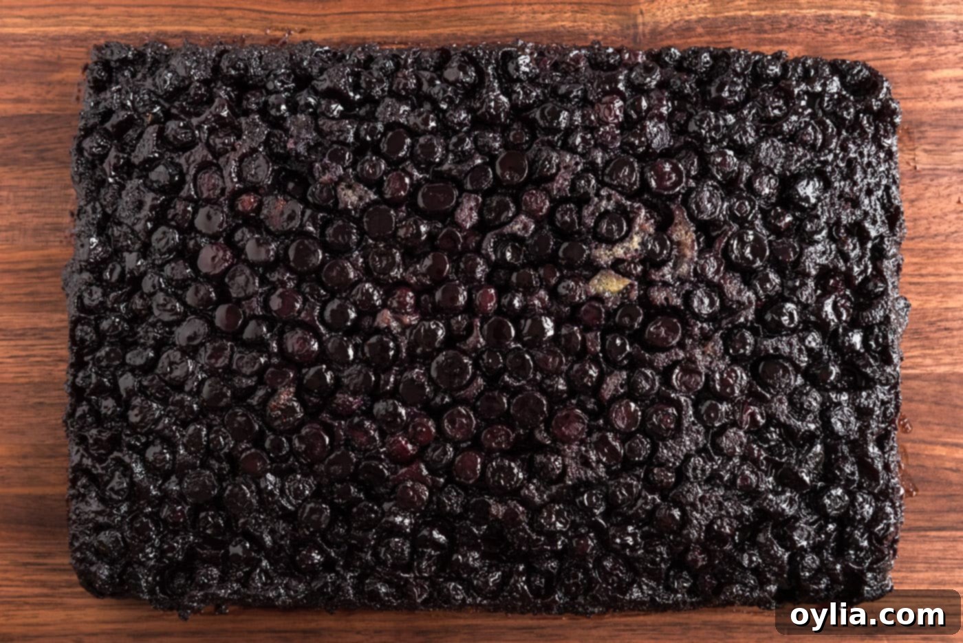 The inverted blueberry upside down cake, showcasing the glistening caramelized berry topping, on a serving board