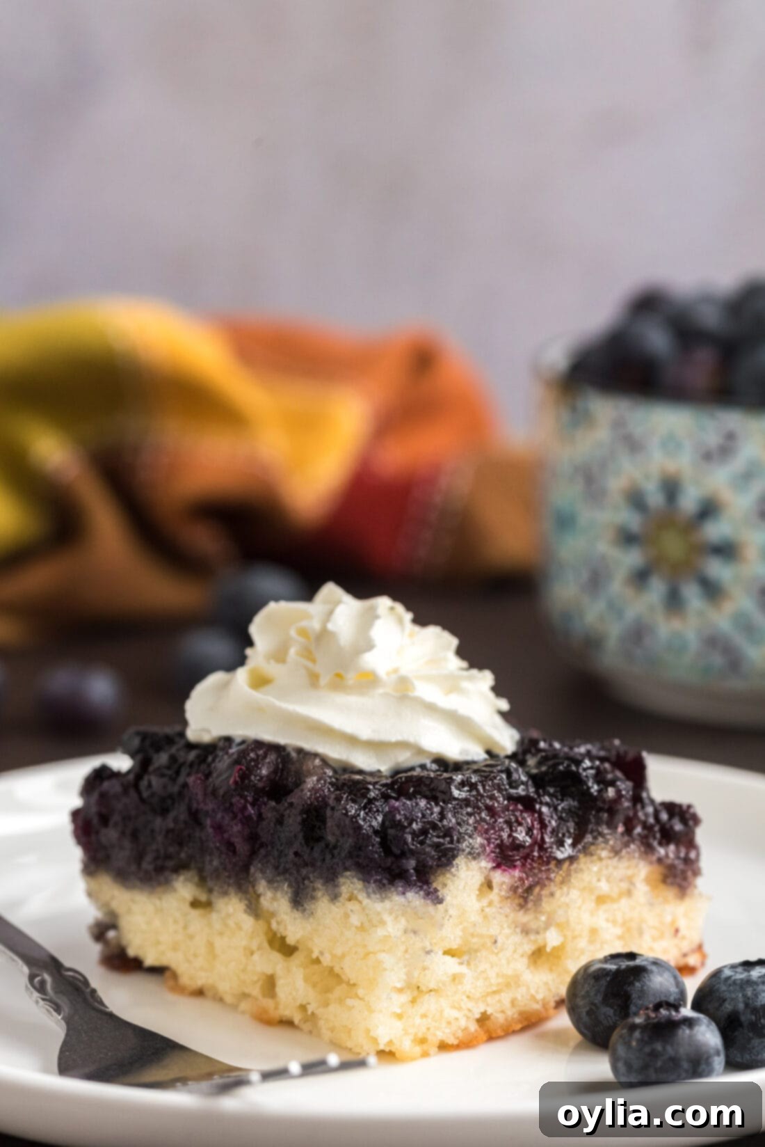 A delectable slice of Easy Blueberry Upside Down Cake on a plate, garnished with a dollop of whipped cream