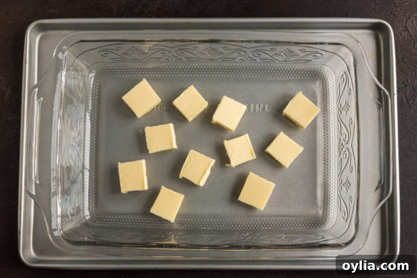Pats of butter placed evenly on the bottom of a 13x9 baking dish before melting