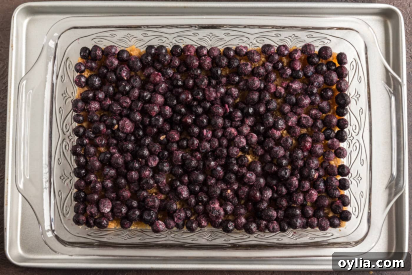 Blueberries scattered in an even layer over the brown sugar and butter mixture in the baking dish
