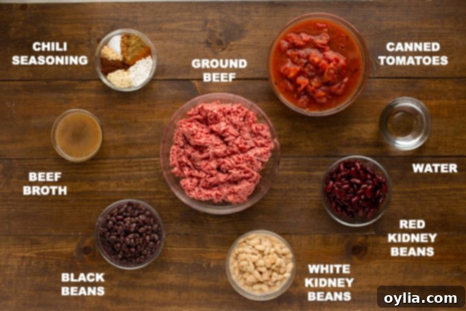 A selection of fresh and canned ingredients for 3 bean chili, including ground beef, fire-roasted tomatoes, dark red kidney beans, black beans, white kidney beans, beef broth, and homemade seasoning mix.