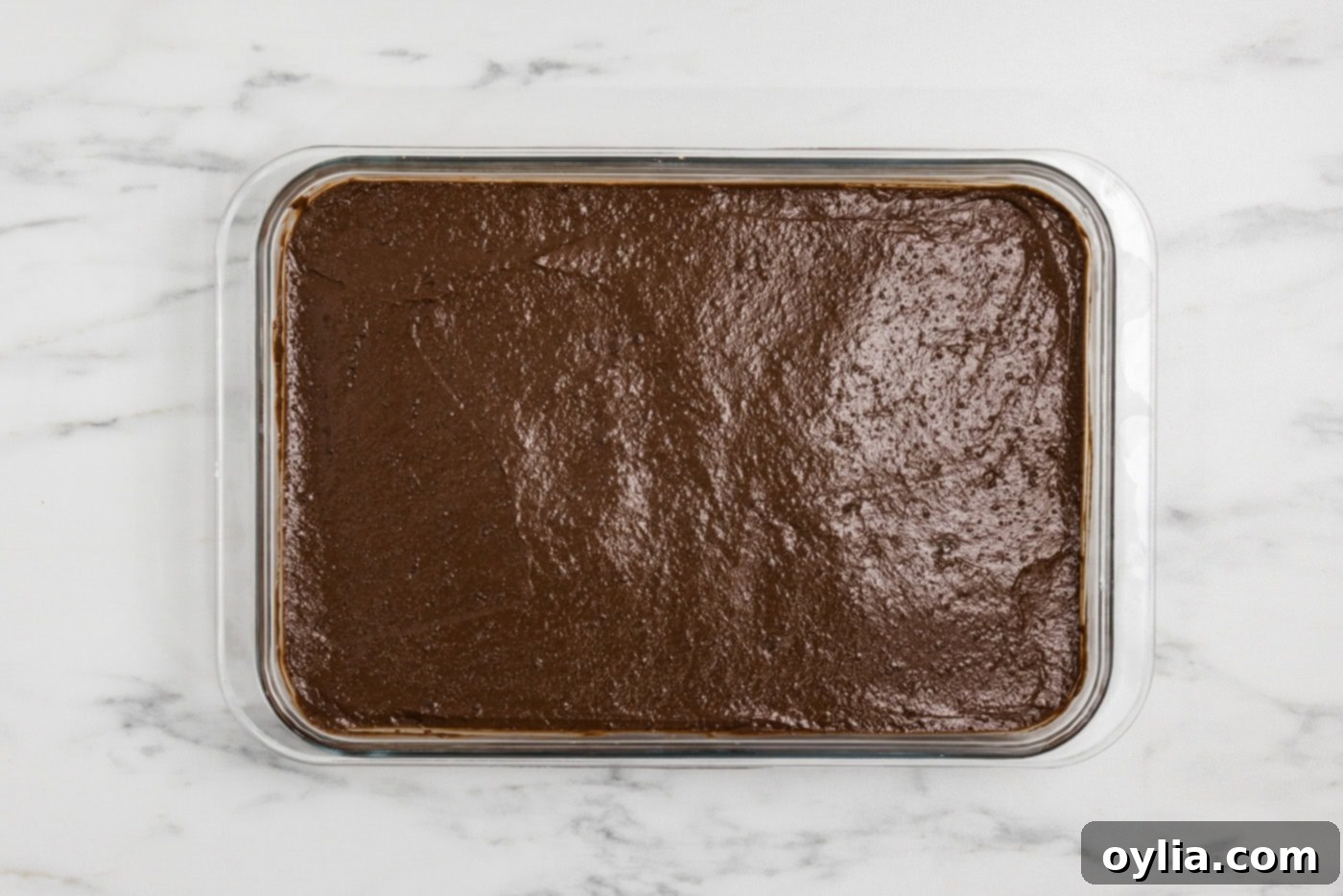 chocolate pudding layer spread over the cheesecake and graham cracker crust in a baking dish