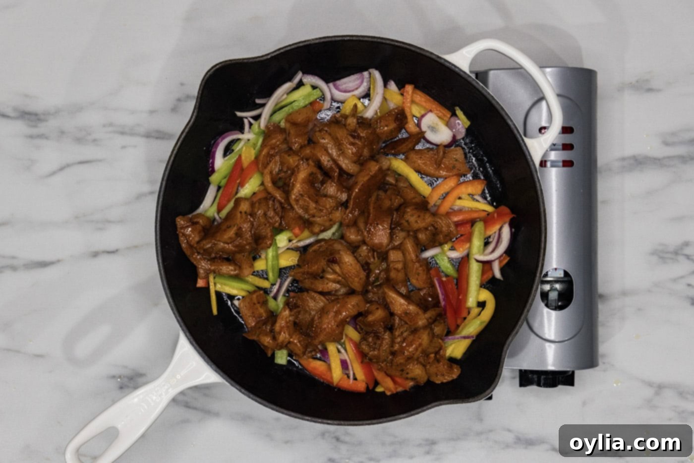 fajita chicken added to skillet with bell peppers and onions