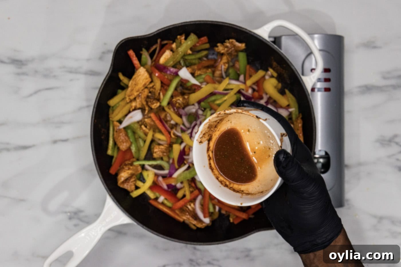 pouring remaining marinade into skillet with chicken fajitas