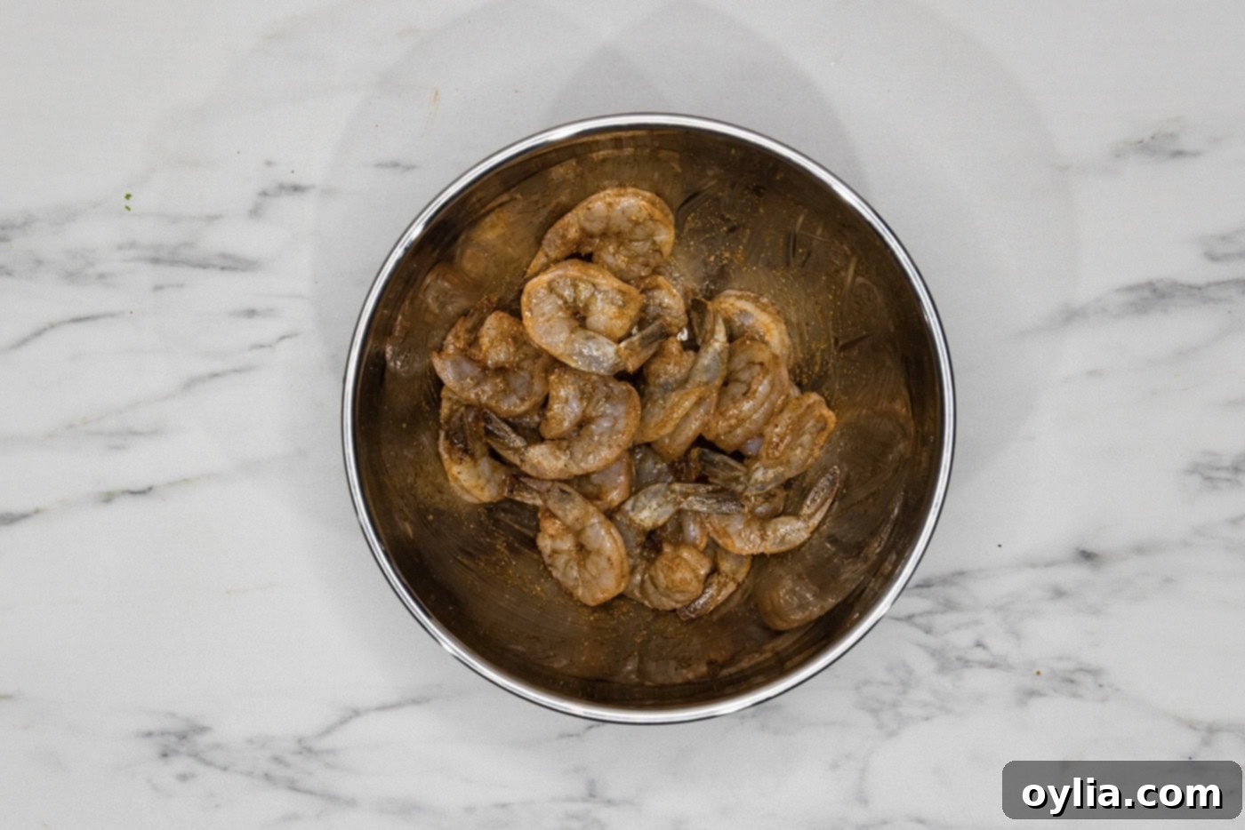 Raw shrimp in a bowl, perfectly tossed with olive oil and spices, ready for broiling