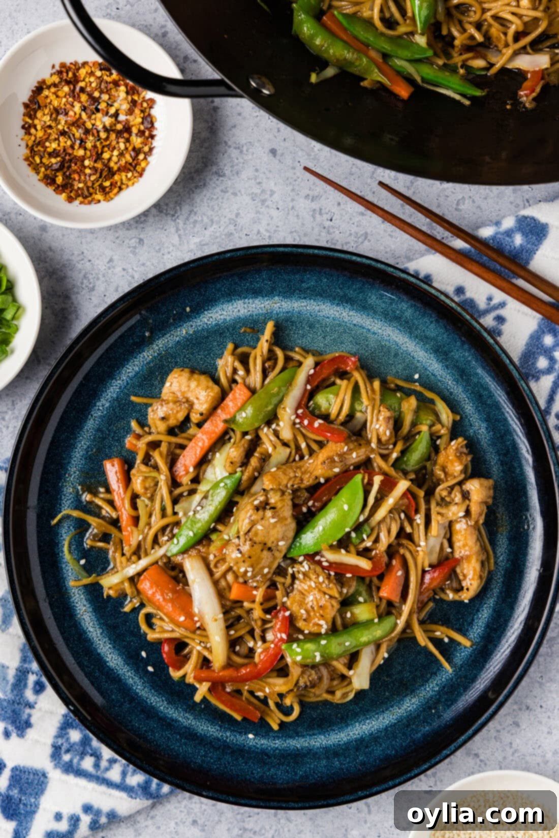 Plate of Chicken Lo Mein with a wok behind it