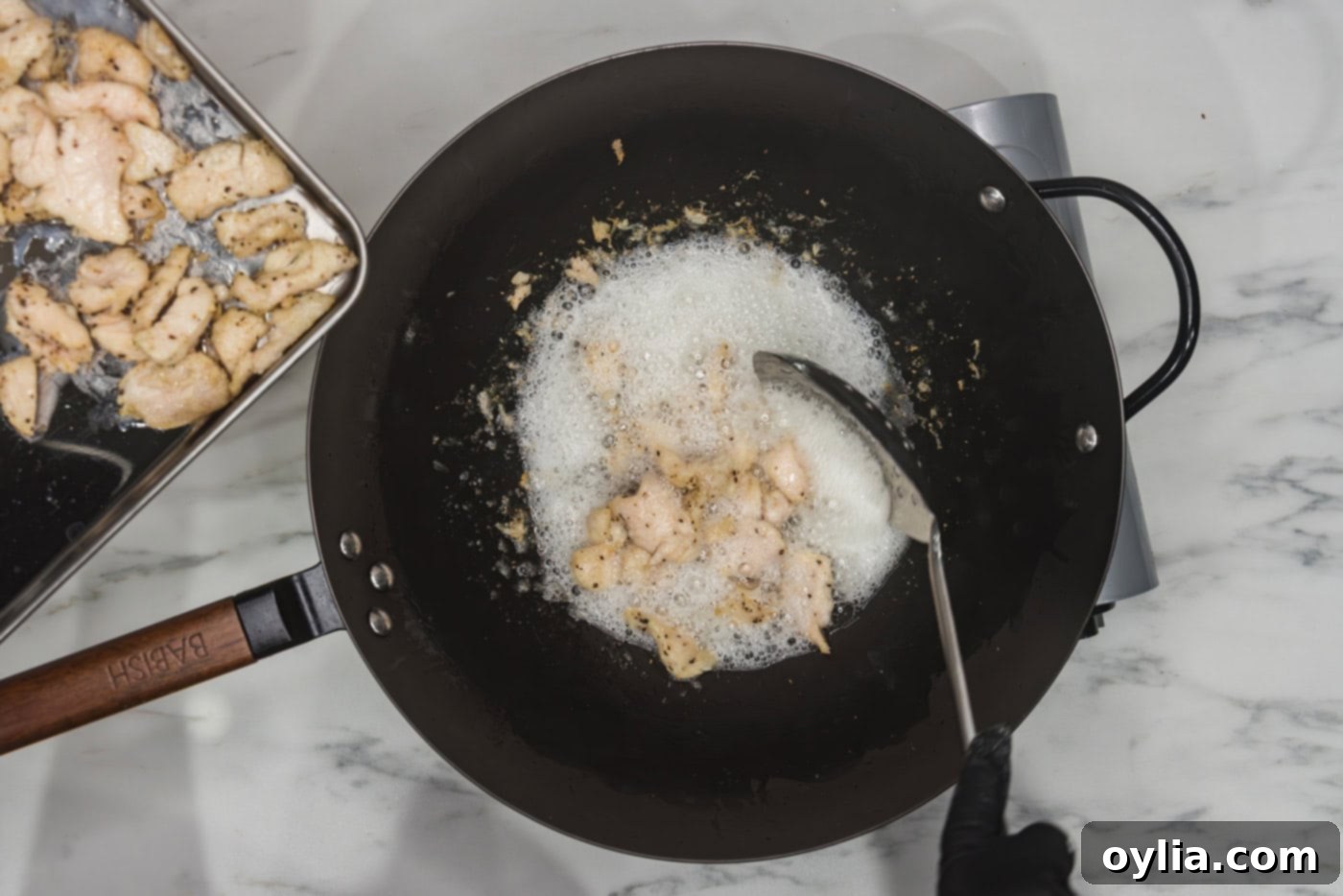 removing chicken from wok of oil with a spoon