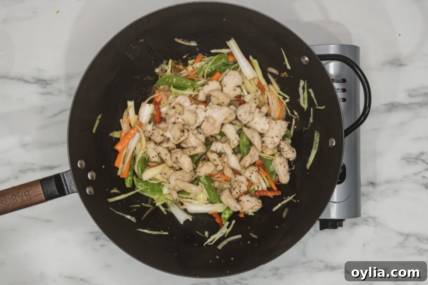 cooked chicken pieces added to wok with stir fried veggies