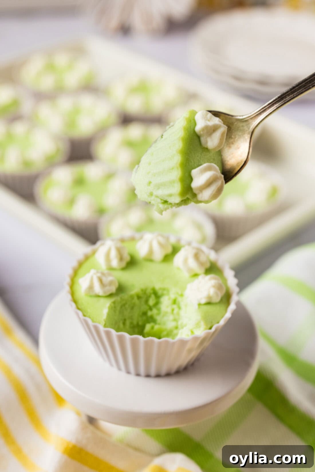 A spoonful of creamy keto lime cheesecake filling held above a finished cheesecake bite, showing its luscious texture.