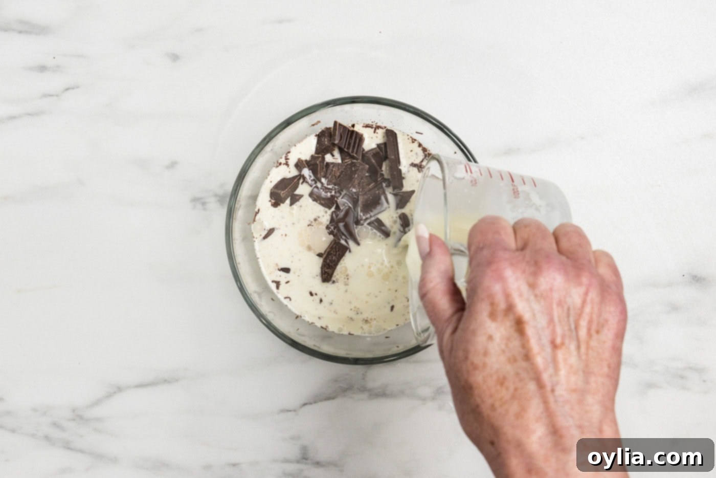 pouring hot cream over chopped chocolate in a bowl