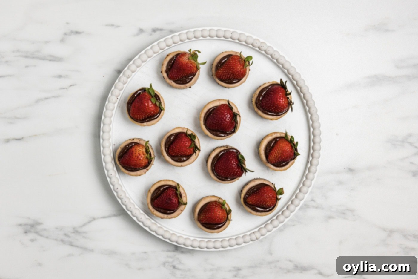 overhead of mini strawberry cheesecakes topped with ganache and strawberries