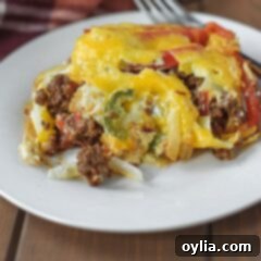 A generous serving of John Wayne Casserole on a plate, topped with melted cheese, ready to eat.