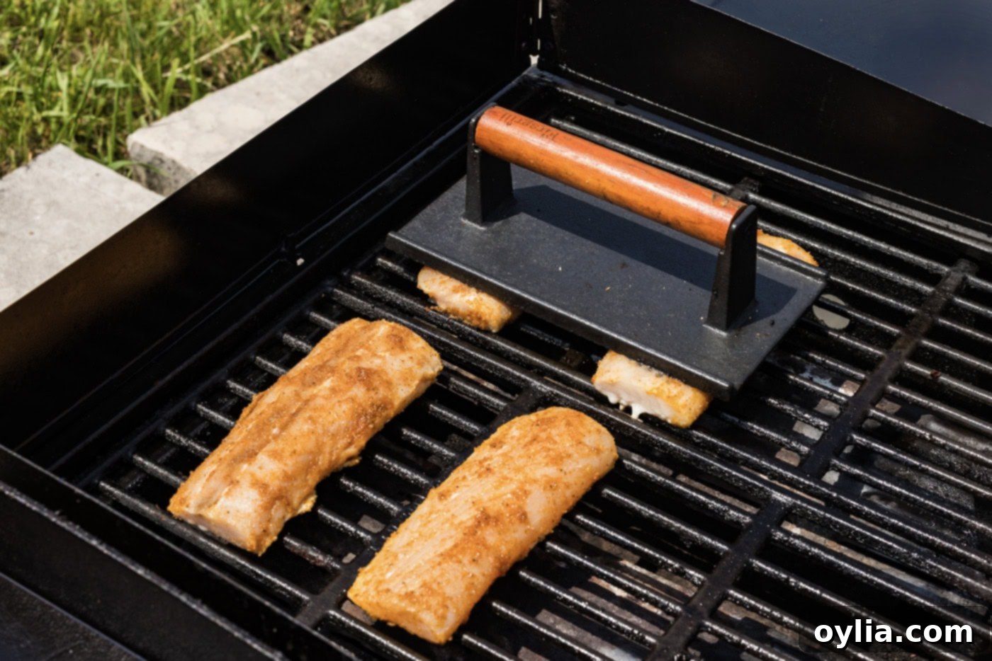 hamburger press over mahi mahi filets on a grill