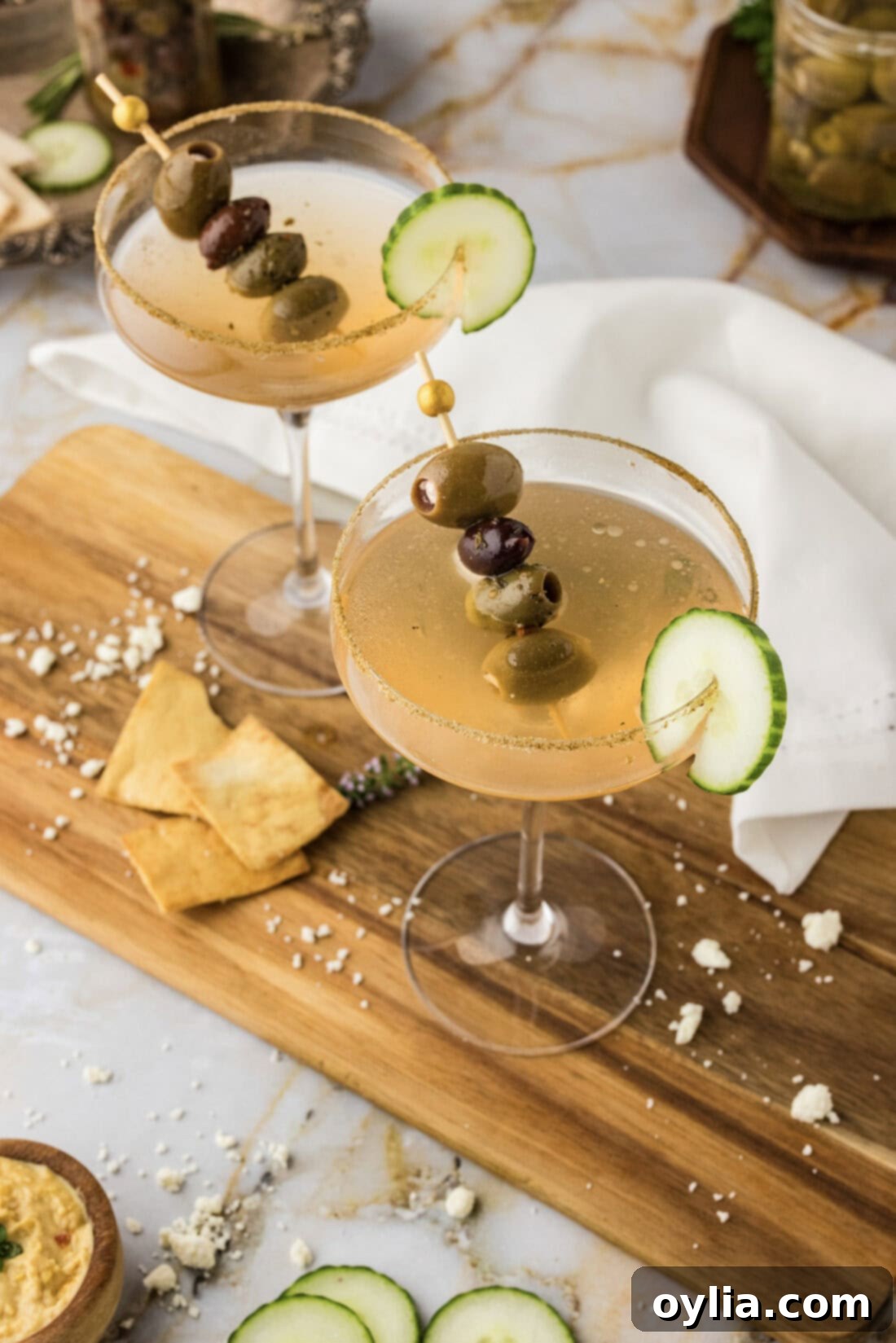 Overhead photo of two Dirty Greek Martinis with celery salt rims and olive garnishes.